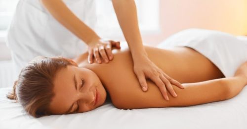 Massage therapist giving back massage to woman